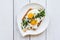 Fried egg with two yolks on bread with chopped greens on a white dish