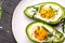 Fried eggs in avocado with fresh herbs and spices. Avocado stuffed with eggs. Delicious breakfast or snack on a light background,