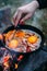 Fried eggs with bacon in a pan in the forest. Food at the camp. Fried egg with bacon on fire.