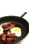 Fried eggs & bacon in skillet vertical