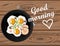 Fried eggs and bacon top view on wooden table with good morning lettering