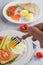 Fried eggs, bread, carrots and tomatoes on a white plate for breakfast, Selective focus handheld with a fork