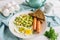 Fried eggs for breakfast on a white plate. Fried eggs with sausages and zucchini, two slices of rye bread, parsley. White wooden b