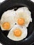 Fried eggs close up. Eggs fried in a black pan. Three egg breakfast. Three fried eggs in a black frying pan.