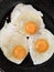 Fried eggs close up. Eggs fried in a black pan. Three egg breakfast. Three fried eggs in a black frying pan.