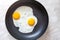 Fried eggs cooked in frying pan for breakfast, top view