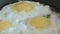 The fried eggs cooked on a pan close up