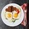 Fried eggs with fresh vegetables and toast in shape of heart on white plate