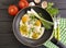 Fried eggs in a frying pan,knife fork breakfast rustic , green onions, tomato, black wooden background
