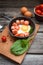 Fried eggs in a frying pan with sausages, cherry tomatoes, herbs, spices and bread for breakfast