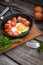 Fried eggs in a frying pan with sausages, cherry tomatoes, herbs, spices and bread for breakfast