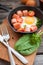 Fried eggs in a frying pan with sausages, cherry tomatoes, herbs, spices and bread for breakfast