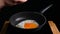 Fried eggs in a frying pan. A woman prepares for breakfast, breaks an egg by pressing.