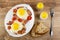 Fried eggs with gammon and cherry tomato in dish, salt and pepper, pieces of bread, fork on wooden table. Top view