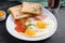 Fried eggs with ham, tomatoes and toasts. Delicious English Breakfast.