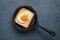 Fried eggs with a heart-shaped yolk on toast in a frying pan. Top view, copy space.