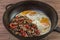 Fried eggs with mushrooms, onions and red pepper in a frying pan. Home-cooked food.