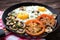 Fried eggs with mushrooms and tomato on dark wooden table