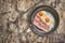 Fried Eggs and Pork Bacon Rashers in Teflon Frying Pan on Old Cracked Peeled Wooden Table