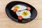 Fried eggs prepared sunny side up and tomatoes on dish