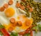Fried eggs with sausages, green peas and bell pepper