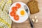 Fried eggs with slices of tomatoes, fork, bread and garlic