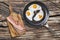 Fried Eggs in Teflon Frying Pan with Bacon Rashers on Cutting Board Set on Old Wood Background