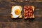 Fried eggs on toast with bacon. Homemade cooked breakfast on a wooden background and a slate board