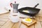 Fried eggs with toast, open book, a cup of coffee and geyser coffee maker on wooden table