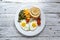 Fried eggs with tomatoes, green beans, corn and toast. English vegetarian breakfast. Light wooden background. Top view. Free space