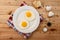 Fried eggs, on a white plate, on wooden background. Top Wiew