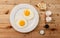 Fried eggs, on a white plate, on wooden background. Top Wiew