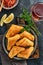 Fried empanadas with cilantro, meat, egg, tomato and chili sauce on black background. Chilean typical dish. Latin American and