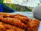 Fried fish cake in a plastic container on the background of the river