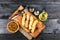 Fried fish in fried fish fillet pangasius on a wooden cutting board with spices, fork and knife on a b