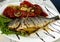 Fried fish with grilled tomatoes and lemon. Small depth of field