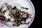 Fried Fish mackerel bone are strip in the white plate with patterned pink flower on black background