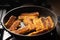 Fried fish sticks breaded in a frying pan. Preparation of frozen fish sticks. Fast food. Dark background