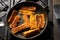 Fried fish sticks breaded in a frying pan. Preparation of frozen fish sticks. Fast food. Dark background