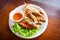 Fried fish with vegetable salad tomato and sauce on white plate wooden table / freshwater fish Mekong River Other names