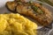 Fried fish woth polenta and herbs on plate with fork