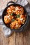 Fried glazed chicken thighs with dried apricots and almonds closeup in a pan. Vertical top view