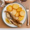 Fried hake served with boiled potatoes and lemon