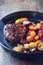 Fried hamburger steak with various cherry tomatoes. Rustic background.