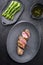 Fried Iberian pork fillet sliced with blanched green asparagus and butter sauce with spice in a cast iron design plate