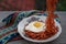 Fried instant noodles are enjoyed with fried eggs on a plate with a typical Indonesian ethnic cloth ornament