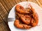 A fried lobster on a white plate, a straw lining under plate, fork, garlic, close up