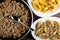 Fried mincemeat, spoon in frying pan, pasta conchiglie in plate, stuffed pasta conchiglie in dish on wooden table. Top view