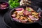 Fried mushrooms with red onions and herbs on dark background