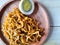 Fried noodles with boiled egg pieces on a wooden plate